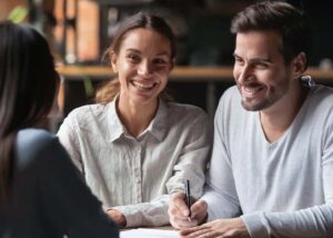 Happy couple sitting in front of a banking representative.