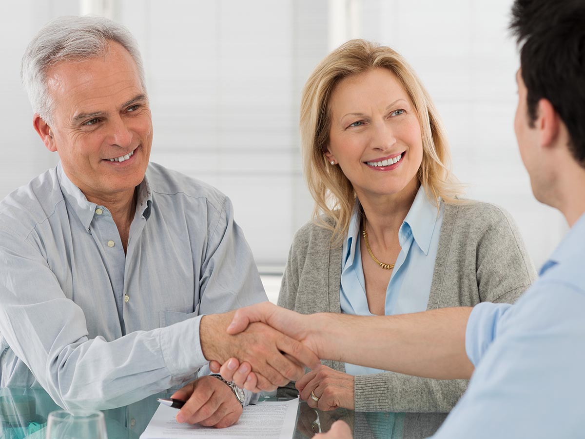 Happy senior couple shaking hands with a businessman