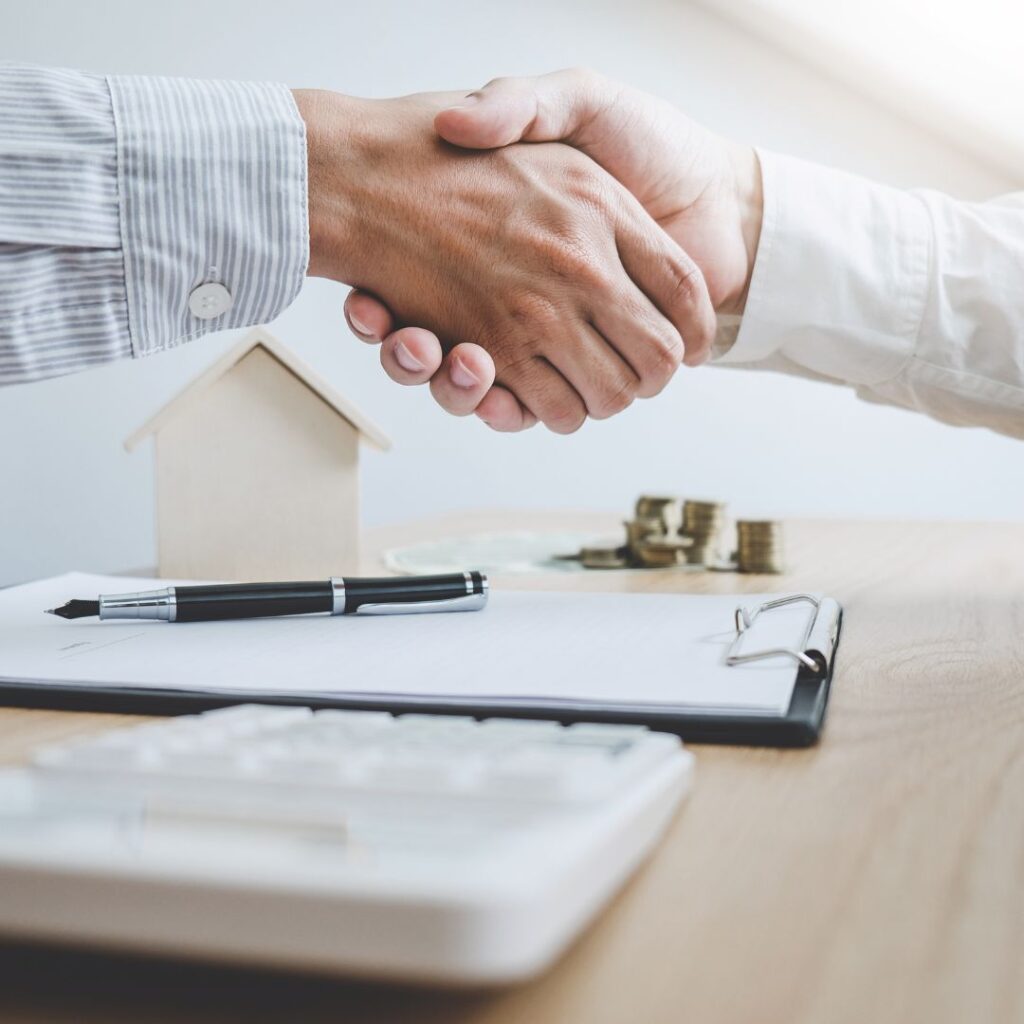People shaking hands over paperwork
