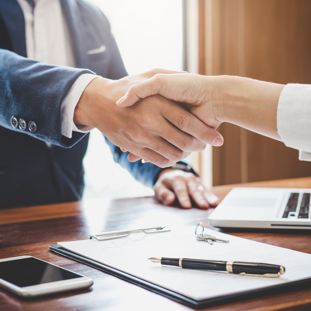business handshake, keys on desk