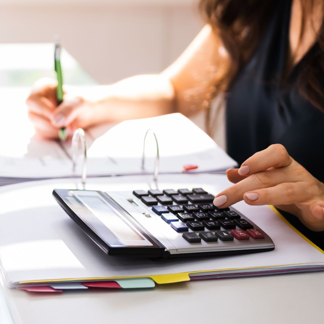 a person doing paperwork and using a calculator