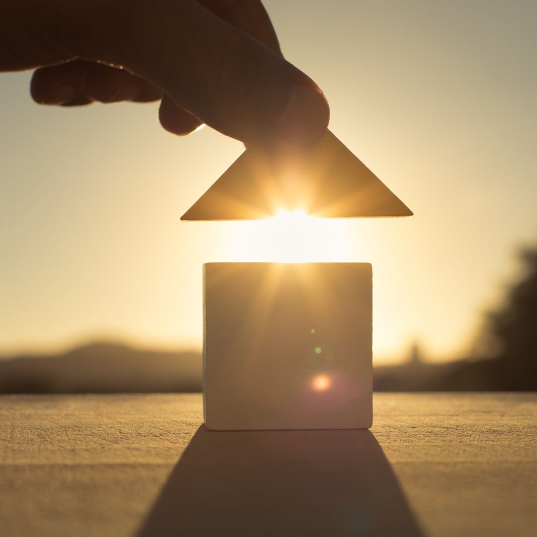 person putting a roof on a toy house
