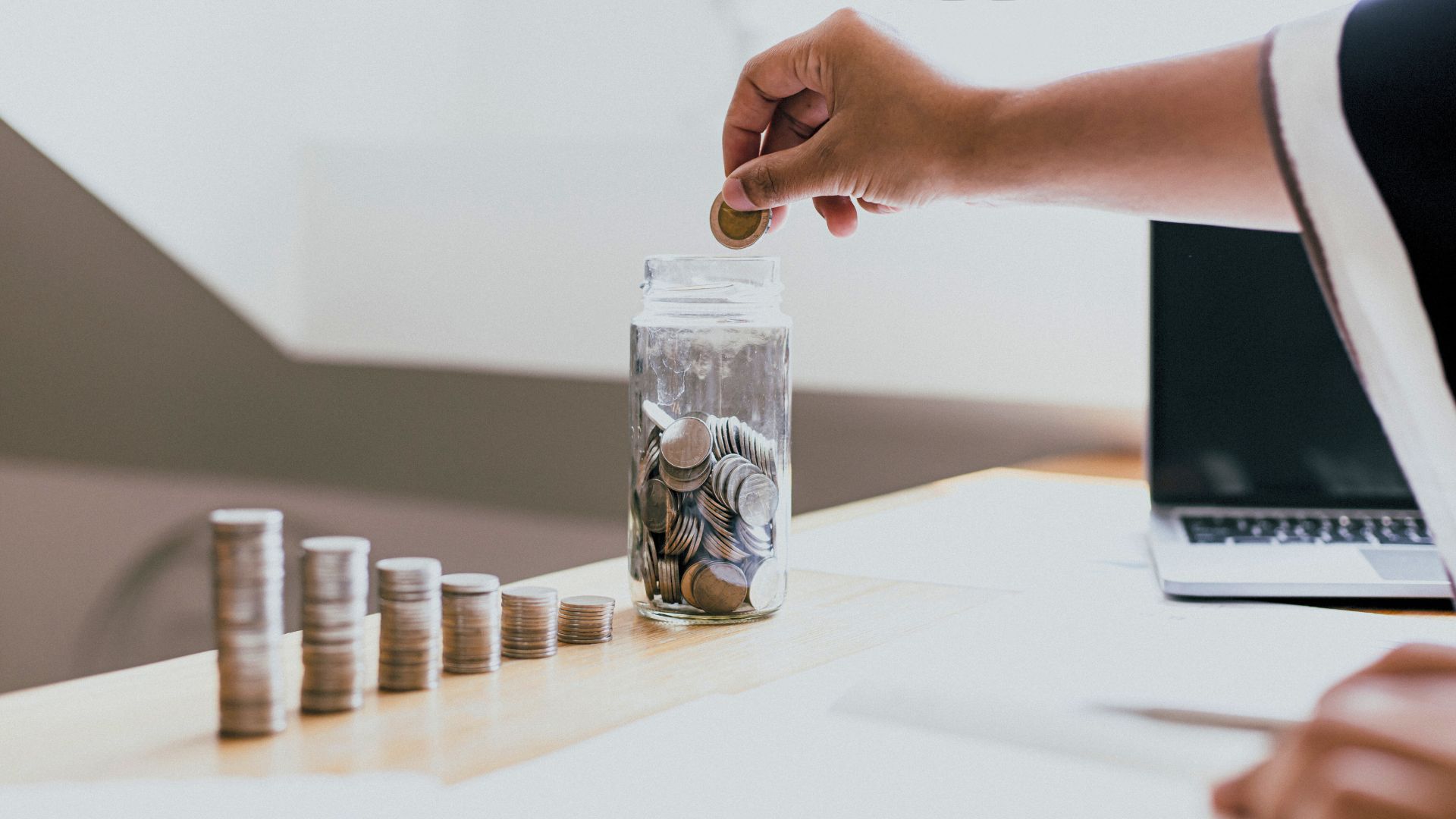 A person stacking coins and putting coins in a jar